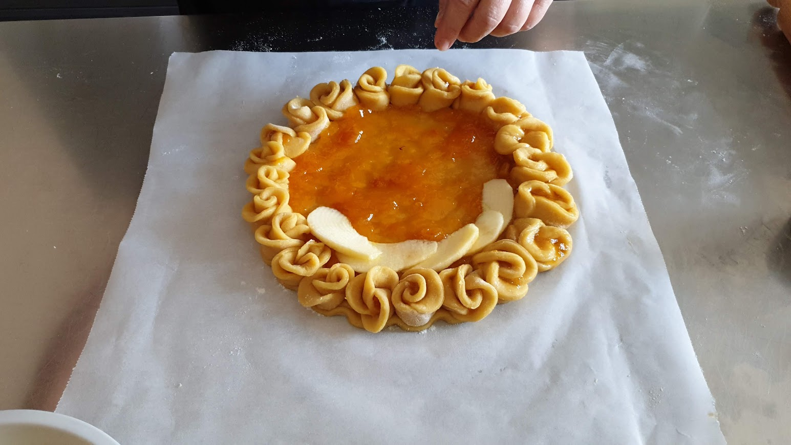Disposizione delle fettine di mela sulla crostata con bordo di roselline